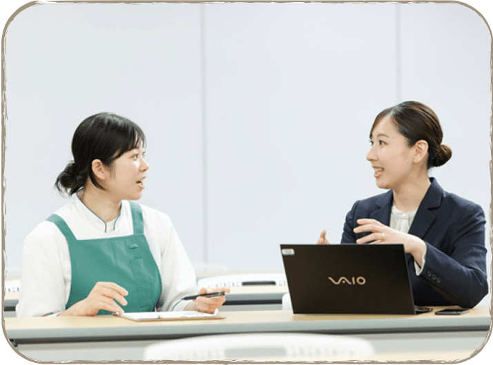 二人の女性がテーブルに座って話をしている様子。